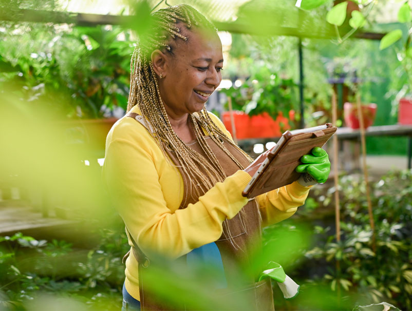 Black woman using tablet in greenhouse